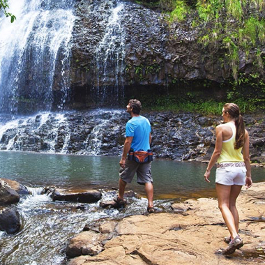 A couple walking up to a tropical waterfall